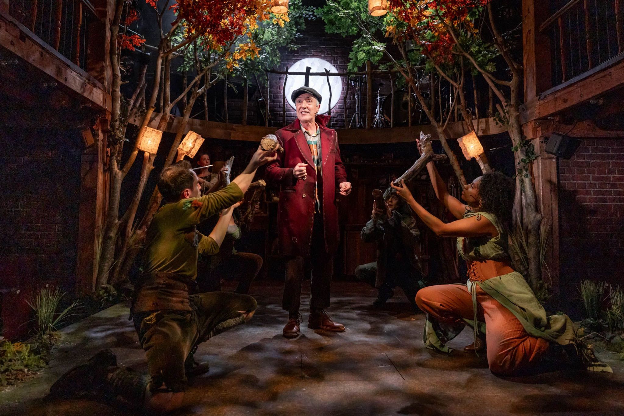 A production shot of Geppetto surrounded by logs held by the company 