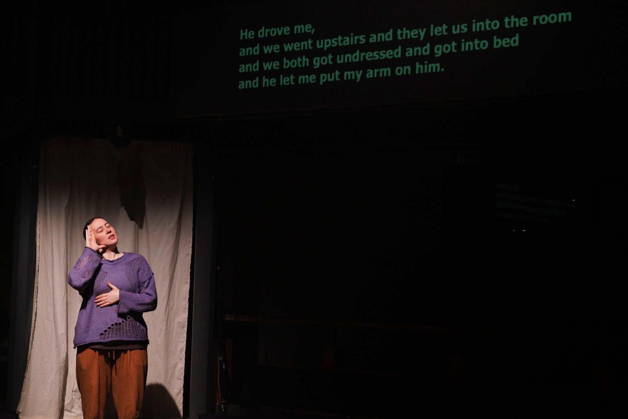 A photo of the Katie Erich, the actor playing Alice signing during the show with the captions next to her.